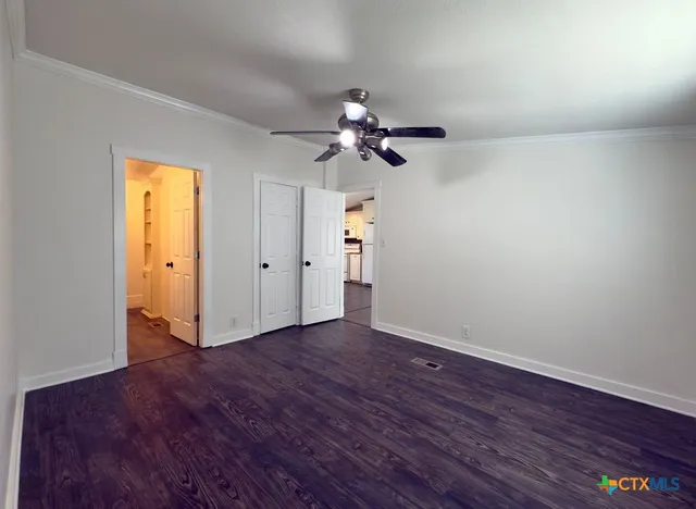 a view of an empty room with chandelier fan and wooden floor
