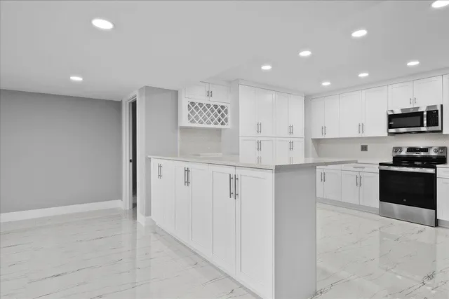 a kitchen with granite countertop white cabinets and stainless steel appliances