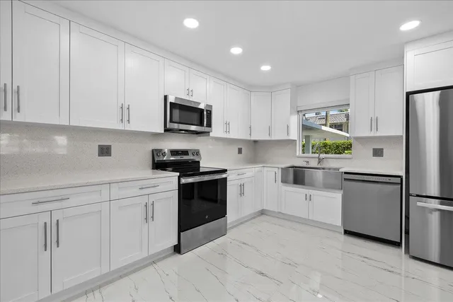 a kitchen with white cabinets and stainless steel appliances