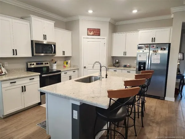 a kitchen with stainless steel appliances a stove a sink a microwave a refrigerator and white cabinets