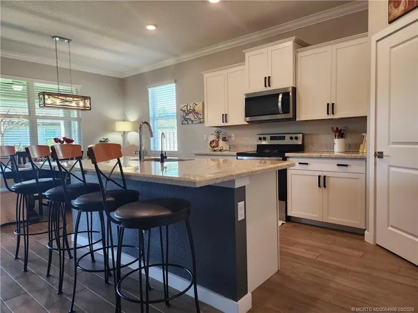 a kitchen with stainless steel appliances granite countertop a table chairs microwave and sink