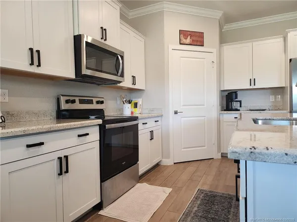 a kitchen with stainless steel appliances granite countertop a refrigerator stove a sink and dishwasher with wooden floor