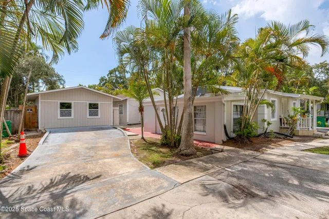 a view of a house with a small yard plants and large tree