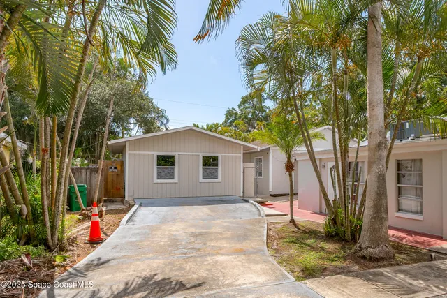 a backyard of a house with table and chairs under an umbrella