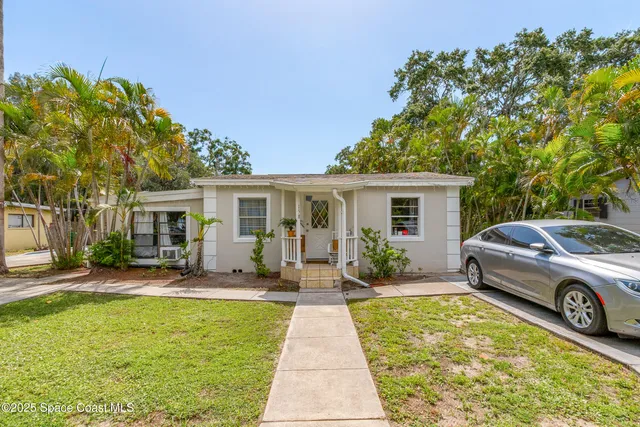 a front view of a house with a garden and trees
