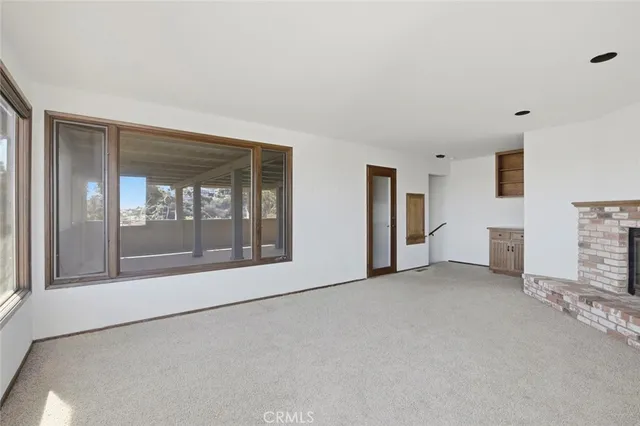 a view of empty room with floor to ceiling window and fireplace