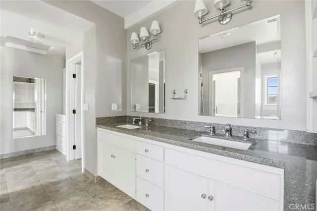 a bathroom with a granite countertop double vanity sink mirror and