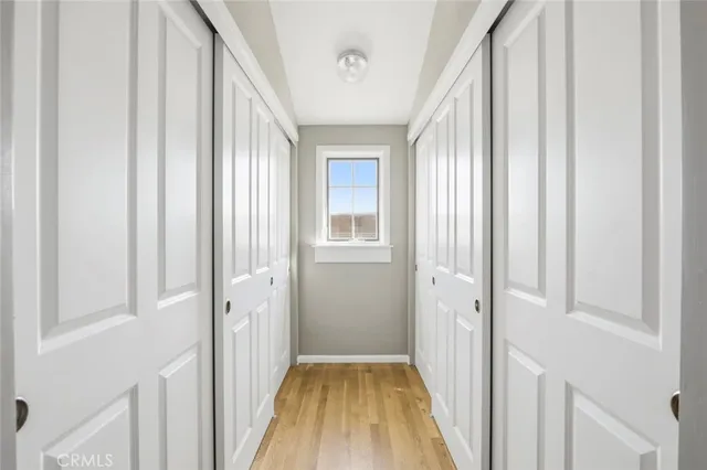 a view of a hallway with wooden floor and a bathroom