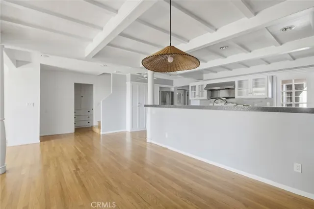 a view of an empty room with wooden floor and a ceiling fan