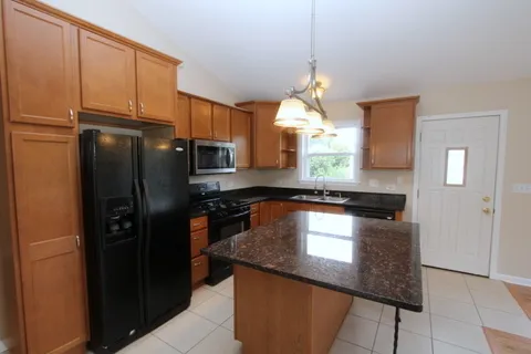a kitchen with granite countertop a refrigerator a stove and a sink