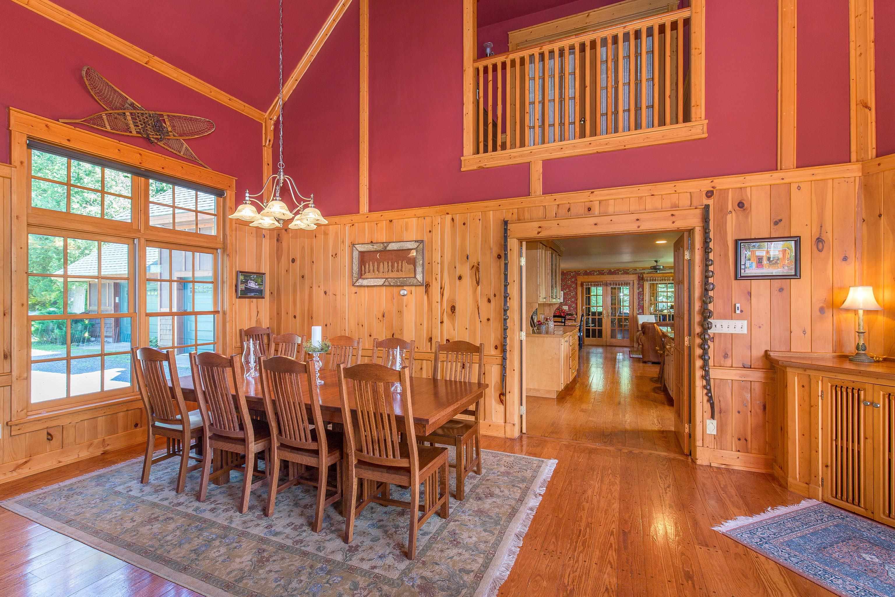 89405 Jack Pine Road Cornucopia, WI 54827 - Photo 25 of 60 Dining room featuring high vaulted ceiling, wood walls, a chandelier, hardwood / wood-style floors, and crown molding