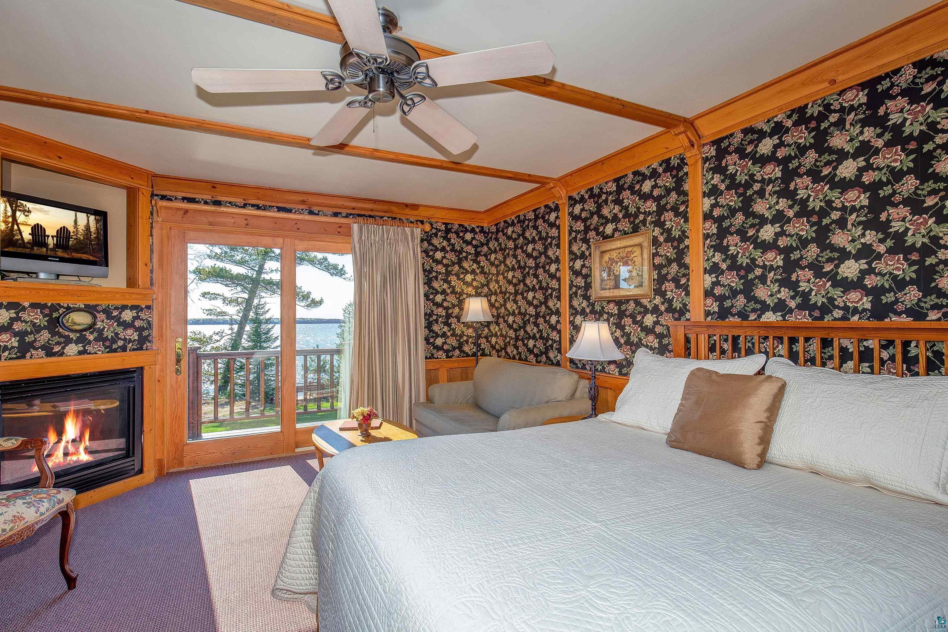 89405 Jack Pine Road Cornucopia, WI 54827 - Photo 34 of 60 Bedroom with wallpapered walls, access to outside, a glass covered fireplace, carpet floors, and wainscoting