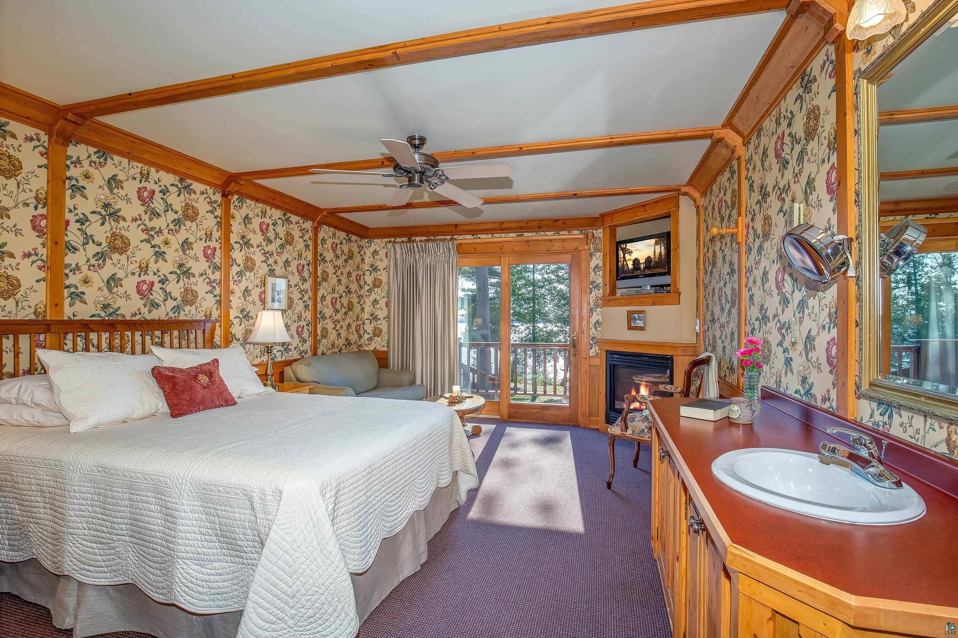 89405 Jack Pine Road Cornucopia, WI 54827 - Photo 36 of 60 Bedroom with wallpapered walls, access to outside, a glass covered fireplace, carpet, and a wainscoted wall