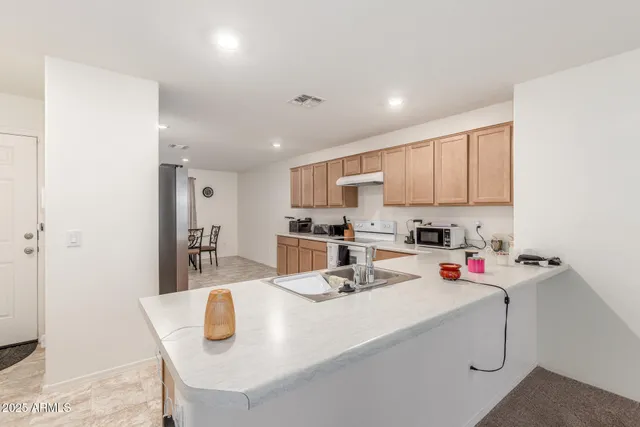 a kitchen with a stove a refrigerator and white cabinets with wooden floor