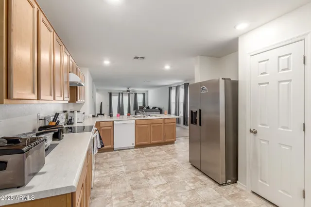 a large kitchen with a refrigerator a sink a stove and cabinets