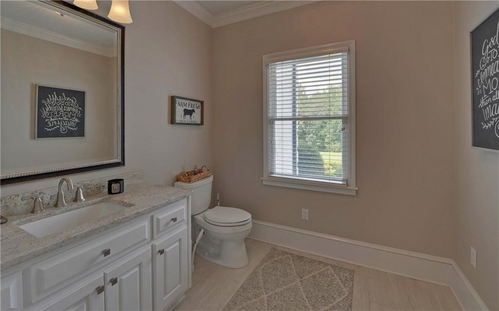 2760 Camp Branch Road Buford, GA 30519 - Photo 23 of 73 a bathroom with a granite countertop toilet a sink a mirror and a window
