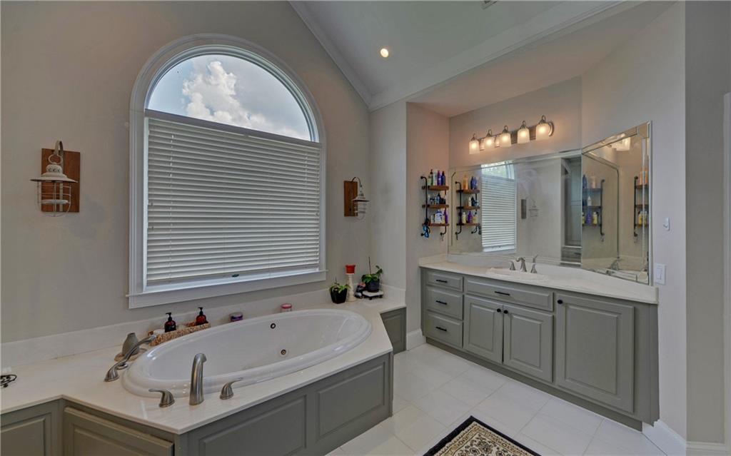 2760 Camp Branch Road Buford, GA 30519 - Photo 32 of 73 a bathroom with a bathtub a sink and a large mirror