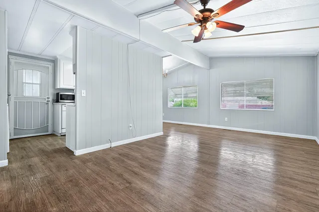a view of an empty room with window and wooden floor
