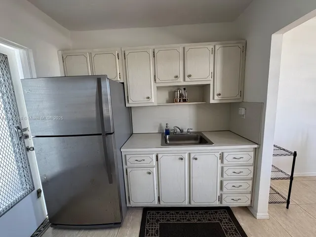 a kitchen with stainless steel appliances a refrigerator a sink and white cabinets