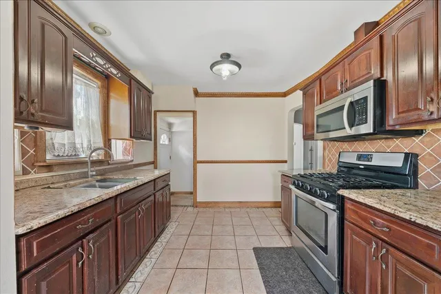 a kitchen with stainless steel appliances granite countertop a stove a sink and a microwave