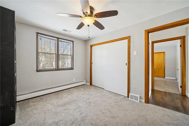 an empty room that has a window and a ceiling fan