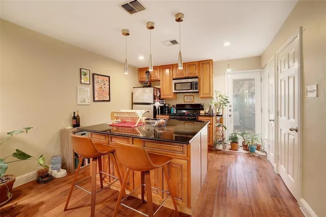 a kitchen with stainless steel appliances a stove a sink dishwasher and a refrigerator with wooden floor
