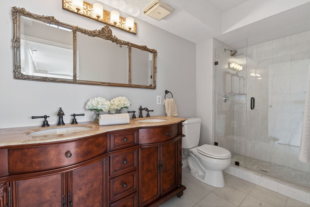 1731 Beacon Street, Unit 1210 Brookline, MA 02445 - Photo 12 of 32 a bathroom with a granite countertop sink a toilet and a mirror