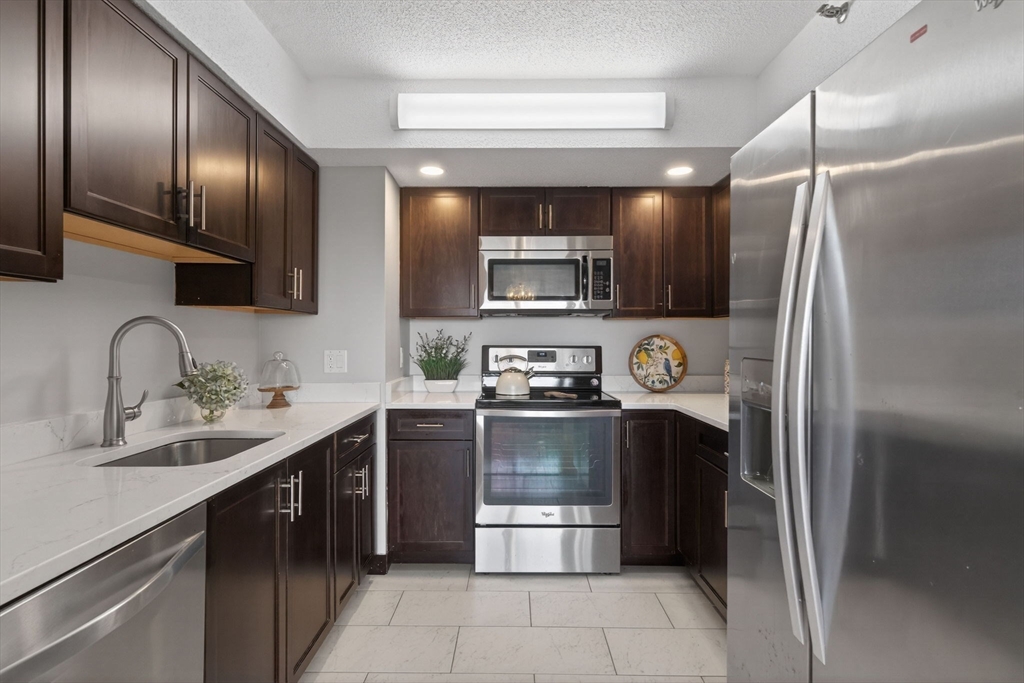 1731 Beacon Street, Unit 1210 Brookline, MA 02445 - Photo 10 of 32 a kitchen with stainless steel appliances granite countertop a refrigerator and a sink