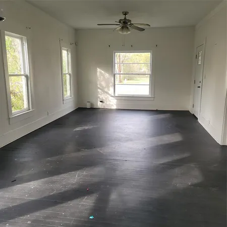 an empty room with wooden floor chandelier and windows