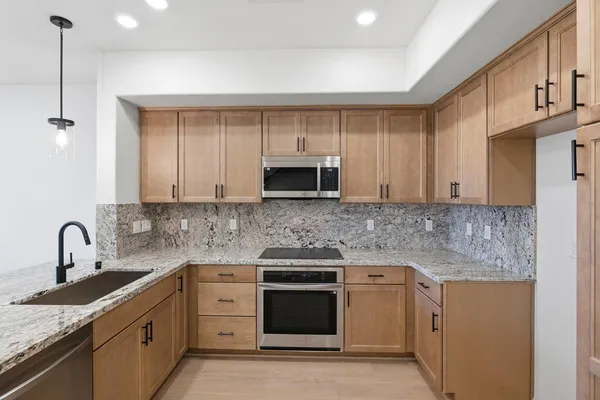 a kitchen with granite countertop a sink stainless steel appliances and white cabinets