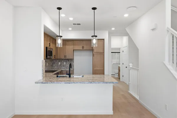 a view of a kitchen with granite countertop a refrigerator a sink and a stove