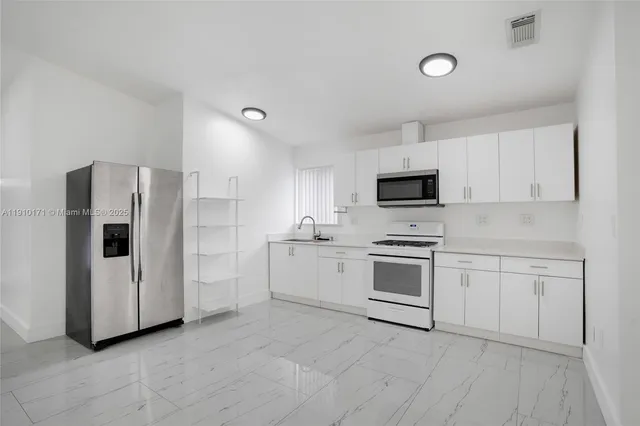 a kitchen with white cabinets and stainless steel appliances