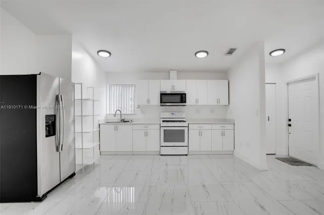 a view of a kitchen with a refrigerator and a sink