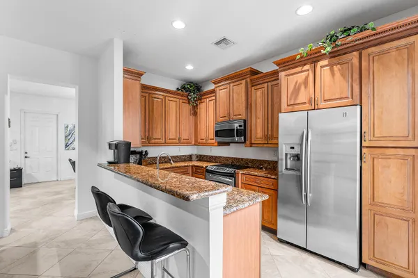 a kitchen with stainless steel appliances granite countertop a refrigerator a stove and a sink