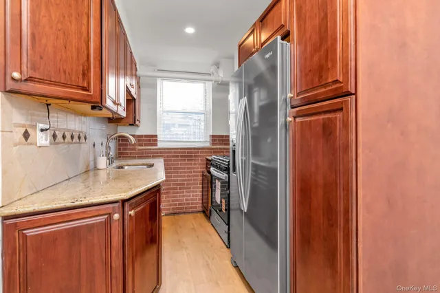 a kitchen with stainless steel appliances granite countertop a refrigerator a sink dishwasher and wooden cabinets with wooden floor