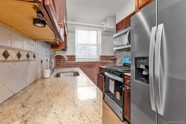 a kitchen with stainless steel appliances granite countertop a refrigerator a stove and a sink