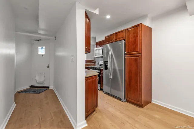 a view of hallway with stainless steel appliances granite countertop cabinets and a refrigerator