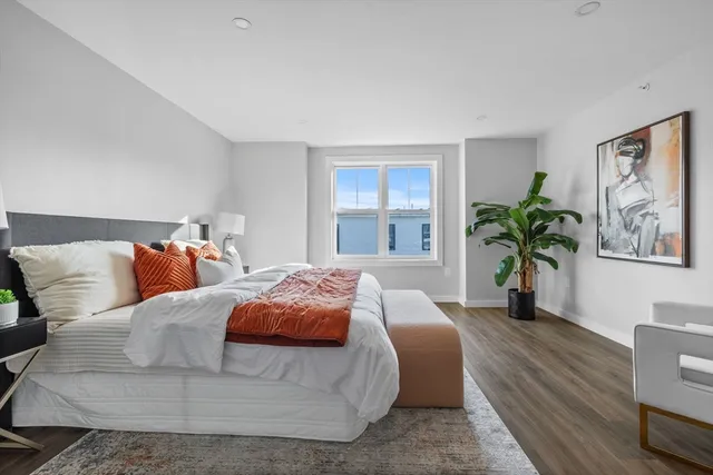 a bedroom with a large bed a potted plant and a window