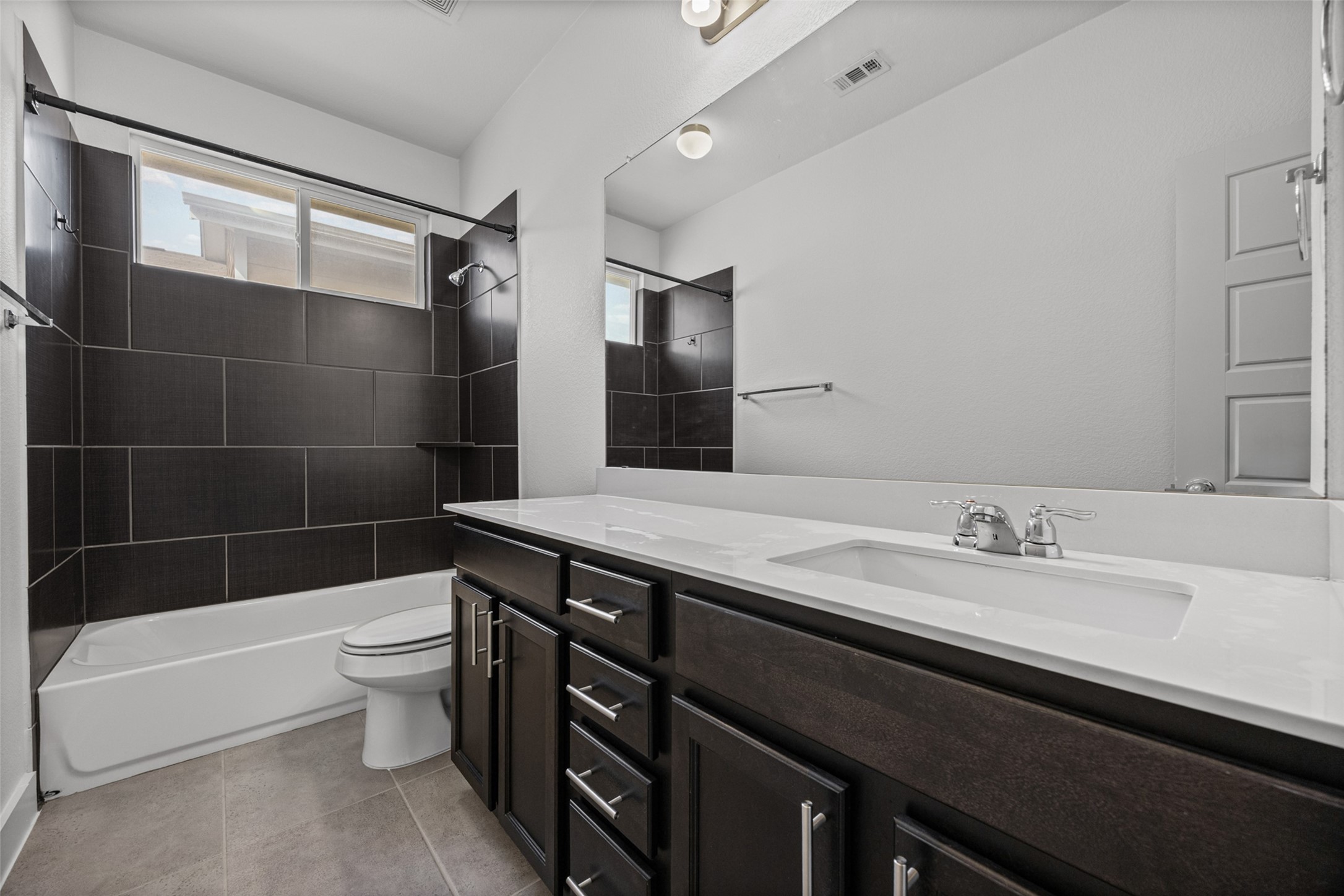 2303 Capulet Street Austin, TX 78741 - Photo 19 of 24 The upstairs secondary bathroom features a full tub and shower combination with modern tile surround. A long vanity offers generous counter space and convenient storage.