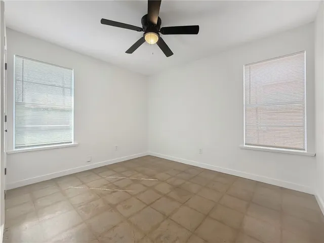 an empty room with windows and fan