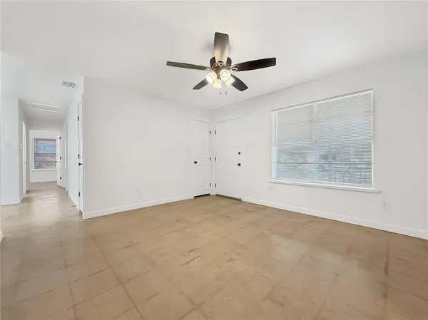 an empty room with windows and fan