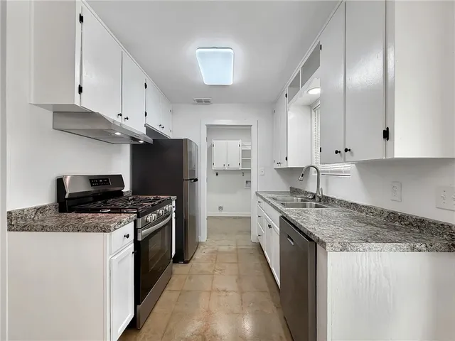 a kitchen with stainless steel appliances granite countertop a stove a sink and a refrigerator