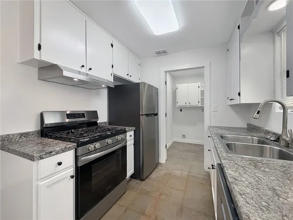 a kitchen with stainless steel appliances granite countertop a stove a refrigerator and a sink