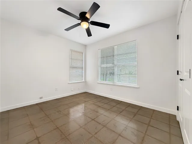 an empty room with windows and fan