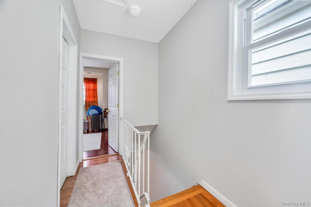 89-13 84th Street Queens, NY 11421 - Photo 32 of 34 Hallway featuring light gray walls, wood-finish flooring, white trim, and a white painted banister