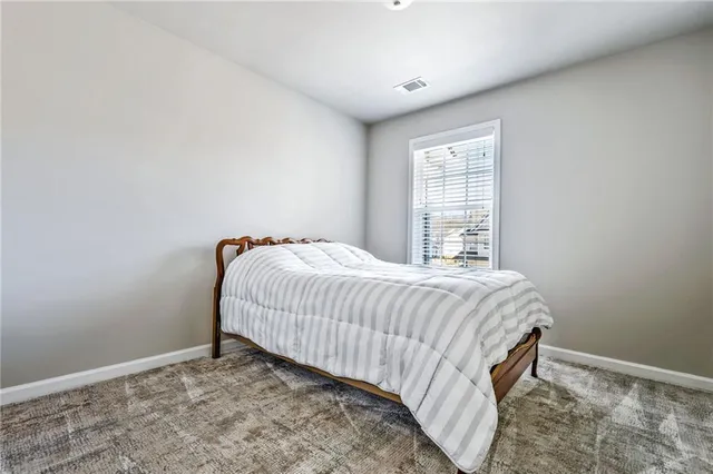 a bed sitting in a spacious bedroom next to a window