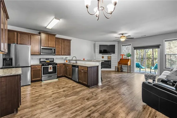 a kitchen with stainless steel appliances kitchen island granite countertop a stove top oven a sink dishwasher a dining table and chairs with wooden floor