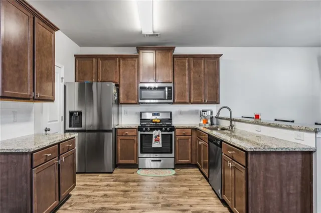 a kitchen with stainless steel appliances granite countertop a sink stove refrigerator and cabinets