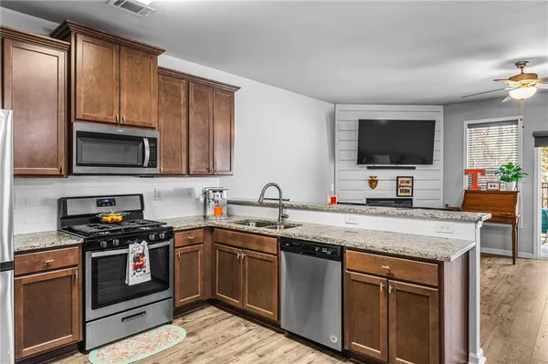 a kitchen with stainless steel appliances granite countertop a sink stove microwave and refrigerator
