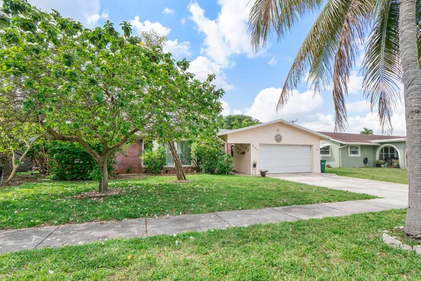 a view of a house with a yard and palm trees